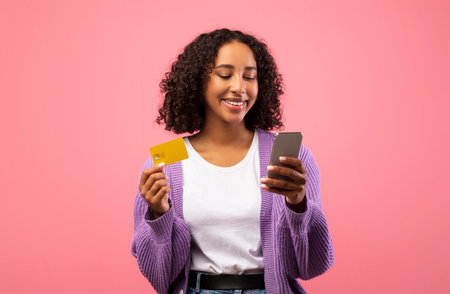 Charming Black Woman Using Smartphone for Online Shopping With Credit Card in Pink Backgroundの写真素材
