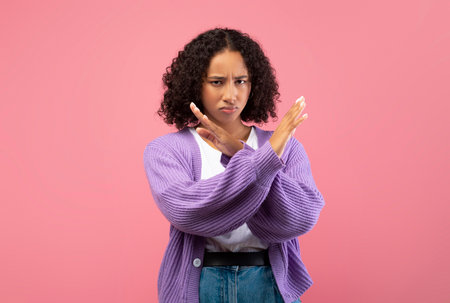 Millennial African American Woman Gestures Stop, Expressing Discontent in Pink Studio Backgroundの写真素材