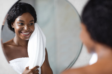 Young African American Woman Enjoying a Refreshing Morning Beauty Routine in Front of the Mirrorの写真素材