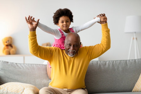 Elderly Man Joyfully Carries Smiling Girl on Shoulders in Cozy Living Room Setting