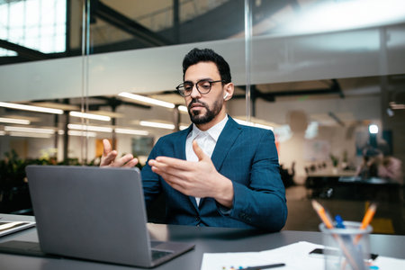 Man in Formal Wear Engages in Video Call From Modern Office Space During Daylight Hoursの写真素材