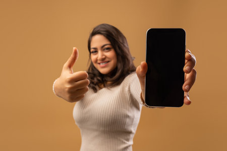 Excited woman showing huge smartphone with blank screen and thumb up, demonstrating mobile app or websiteの写真素材