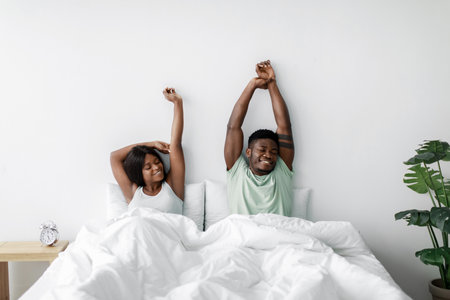 Couple Stretching and Waking up in a Bright Bedroom With a Peaceful Atmosphere in the Morningの写真素材