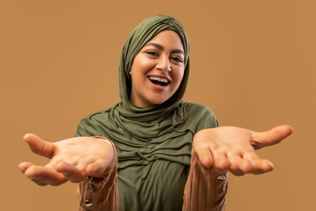 Excited Arab Woman in Hijab Joyfully Reacting to Good News With Hands Spread Wideの写真素材