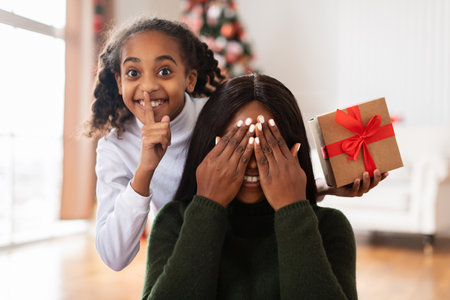Happy Family Enjoys Christmas Surprise With Secret Gift at Home in Festive Atmosphereの写真素材