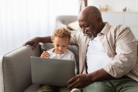 Grandpa and Grandson Enjoy Browsing the Internet Together at Home on a Cozy Couch