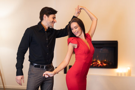 Couple Dancing Joyfully Together in a Cozy Room With a Fireplace During an Evening Gatheringの写真素材