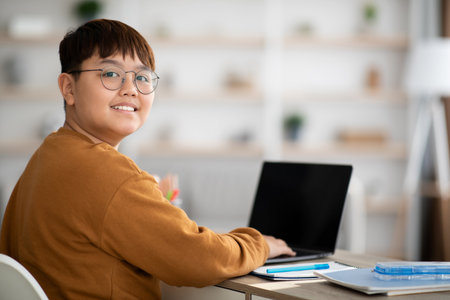 Cheerful Chinese Kid Using Laptop at Home for Online Learning With Copy Space for Contentの写真素材