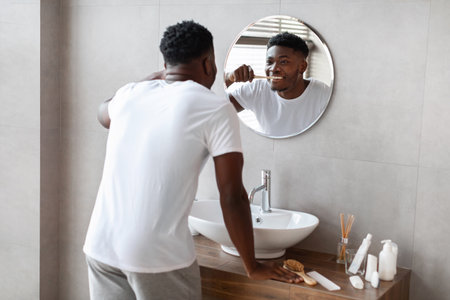Morning Oral Hygiene Routine of an African American Man in a Modern Bathroom Settingの写真素材