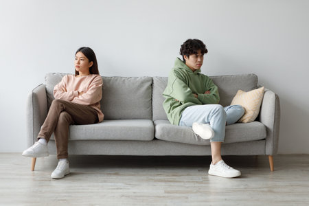 Young Couple Sitting in Silence After an Argument on Their Couch at Homeの写真素材
