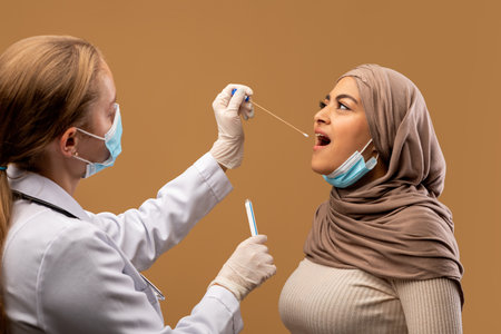 Coronavirus, COVID-19 pcr test concept. Nurse taking oral swab for coronavirus sample test from infected muslim womanの写真素材