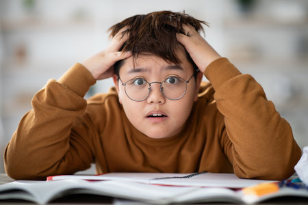 Closeup of Shocked Chinese Boy Struggles With Homework in a Study Settingの写真素材