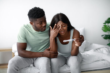 Couple Experiencing a Moment of Surprise While Checking a Pregnancy Test Result in a Bright, Cozy Bedroomの写真素材