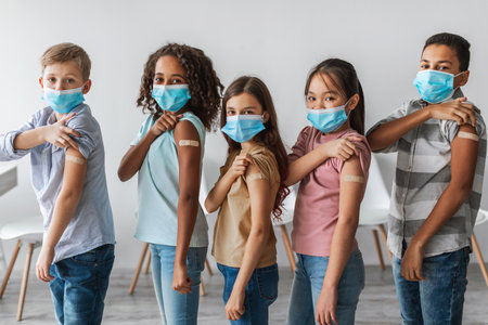 Diverse Group of Vaccinated Children Proudly Showing Arms After Receiving Covid-19 Vaccine Indoorsの写真素材