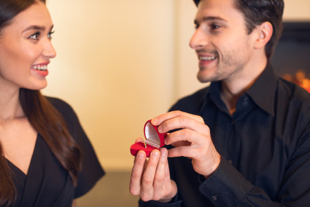 Couple Shares a Joyful Moment During an Engagement Proposal in a Cozy Indoor Setting With Warm Lightingの写真素材