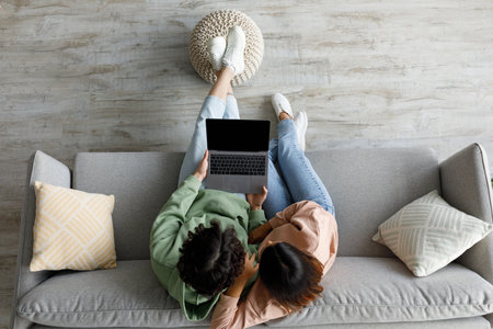 Couple Relaxing on Couch at Home With Laptop, Browsing Website Design Togetherの写真素材