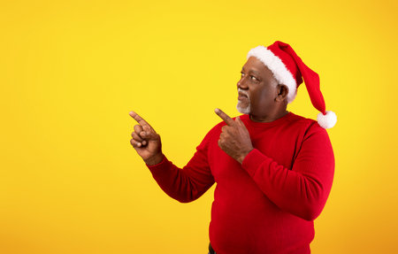 Senior Black Man Wearing a Santa Hat Promotes Christmas Sale With a Cheerful Gestureの写真素材