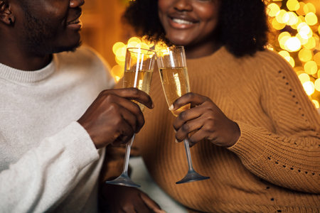 Young Couple Toasting With Champagne Glasses in Festive Christmas Celebration at Homeの写真素材