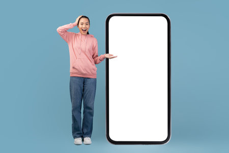 Woman Excitedly Shows Big Smartphone With Empty Screen in Studioの写真素材