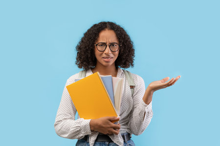 Frustrated Black Female Student Struggling With Homework on Blue Backgroundの写真素材