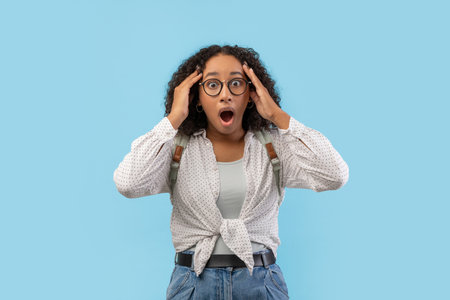 Shocked Young Black Female Student Feels Panic Before College Exams Against Blue Backgroundの写真素材