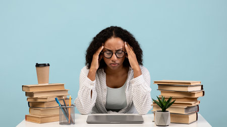Exhausted Black Female Student Struggles With Study Stress While Preparing for Examsの写真素材