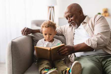 Grandfather and Grandson Enjoy Reading Time Together at Home on a Weekend Afternoonの写真素材