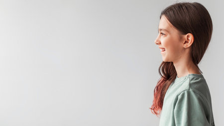 Cheerful Girl Smiling in Profile View on Gray Background Expressing Happiness and Joyの写真素材
