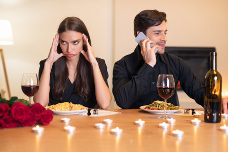 Couple at an Awkward Dinner, One is Distracted by Phone While the Other Looks Frustratedの写真素材
