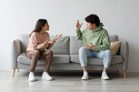 Young Couple Arguing in Living Room Over Relationship Issues During Difficult Timesの写真素材