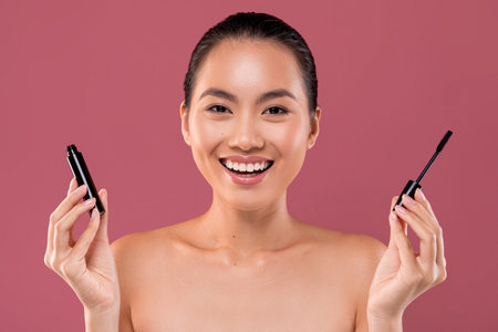 Beautiful Asian Woman Prepares for Party by Applying Mascara With a Smile on Her Faceの写真素材