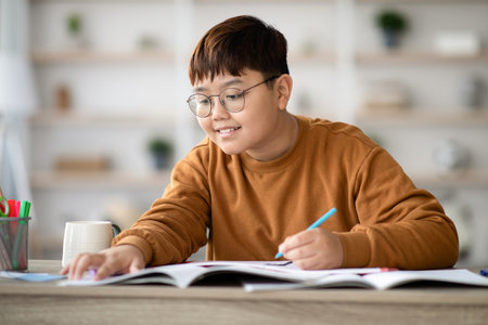 Smiling Asian Schooler Enjoys Doing Homework at a Cozy Study Table in a Home Setting