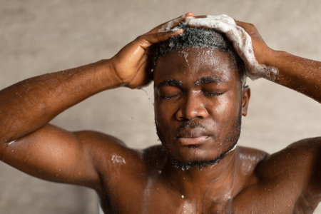 African American Man Enjoying a Refreshing Hair Wash in a Relaxing Indoor Showerの写真素材