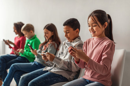 Multiethnic School Kids Engaged With Mobile Phones on Gray Backgroundの写真素材