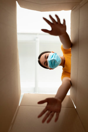 Young Woman in Face Mask Happily Unpacks Delivery Box From Online Shopping Experience