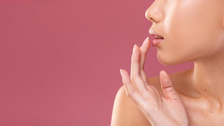 Sensual Young Woman Touching Her Lips Against a Soft Purple Backgroundの写真素材