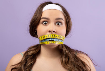 Shocked Plus Size Woman With Measuring Tape on Purple Background Expresses Emotions About Dietの写真素材
