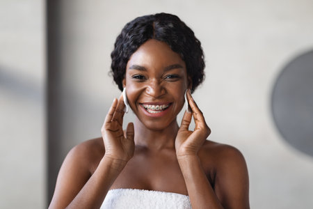 Happy Young Black Woman Enjoying Her Beauty Routine With Cotton Pads at Homeの写真素材