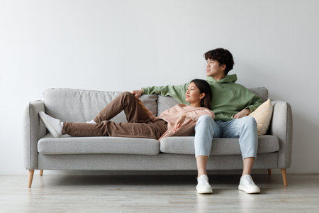 Young Couple Enjoys Quiet Weekend Moments on Couch in Cozy Living Roomの写真素材