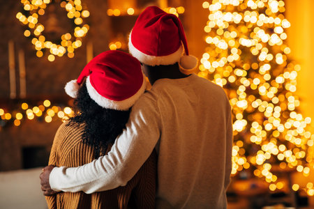 Young Couple in Santa Hats Share a Loving Moment by a Christmas Treeの写真素材