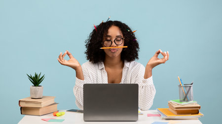 Woman Meditating With Pencils in Hair While Sitting by Laptop on Blue Background