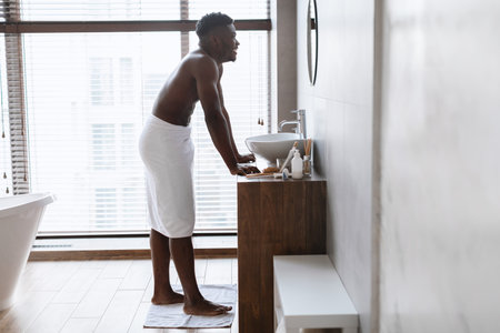 Happy African American Man Enjoying Self-Care in a Modern Bathroom After a Refreshing Showerの写真素材