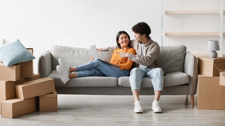 Happy Millennial Couple Planning Their New Home Design While Sitting on Couch