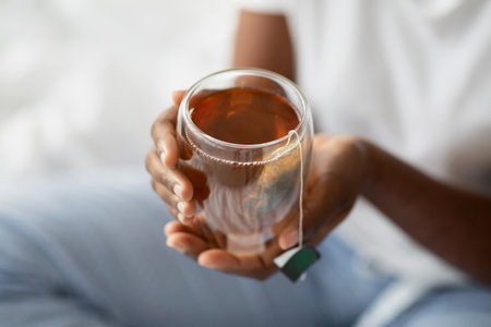 Black Woman in Pajamas Enjoys Herbal Tea in Bed During a Peaceful Morning Momentの写真素材