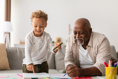 Black Grandfather and Grandson Create Art Together at Home Enjoying Their Weekend Bonding Timeの写真素材
