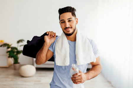 Young Man Preparing for Workout at Home With Towel and Water Bottle in Handの写真素材