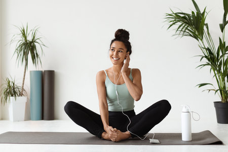 Beautiful Young Athletic Woman Enjoys Music While Practicing Yoga in a Studioの写真素材