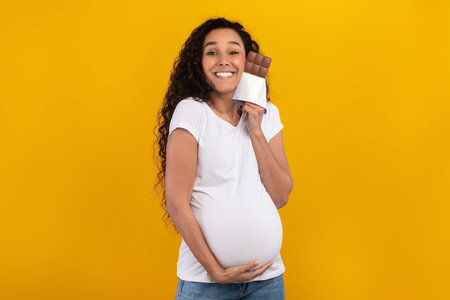 Funny Pregnant Woman Poses With Chocolate in a Bright Yellow Studio Background