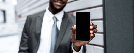 Businessman Offers Smartphone While Standing Against Modern Wall in City