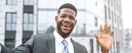 Businessman Greeting With a Smile Outside a Modern Office Building on a Sunny Dayの写真素材